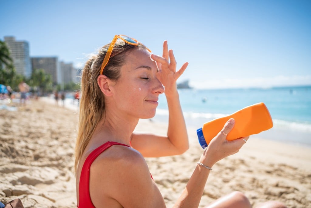Woman On Beach Applying Sunscreen